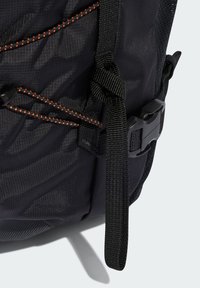 Crni ruksak s teksturiranim tkaninom, podesivim naramenicama, narančastim šavovima i plastičnom kopčom za sigurno zatvaranje.