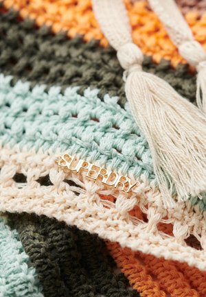 Textil de ganchillo con franjas alternadas en verde menta, crema, oliva, naranja y marrón claro. Una etiqueta dorada de "SUPERDRY" y borlas beige añaden acentos.