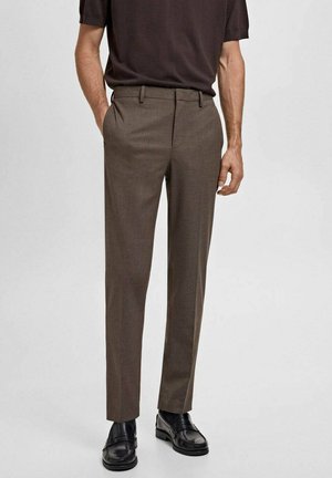 Bruine op maat gemaakte broeken met een platte voorkant en riemlussen, voorzien van zijzakken en een slim fit, gecombineerd met zwarte schoenen.