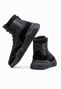 Sneaker alte nere con un mix di materiali in camoscio e rete, design con lacci, suola in gomma e branding "OMBRE" sul lato.