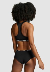 Schwarzes Sportbekleidungs-Set mit einem Racerback-Sport-BH und passenden Unterhosen. Hergestellt aus glattem Material mit Logo-Akzenten am Bund.