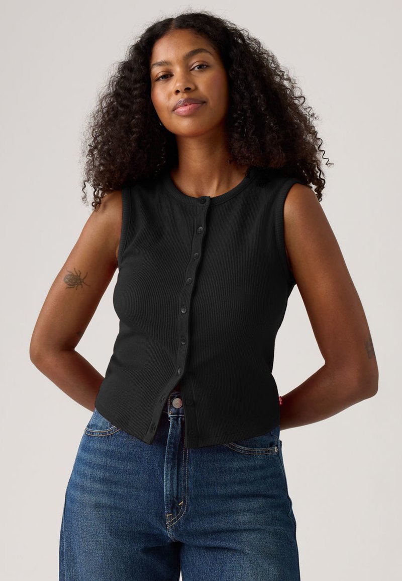 Black ribbed sleeveless top with button front closure, featuring a round neckline and fitted design, paired with high-waisted blue jeans.