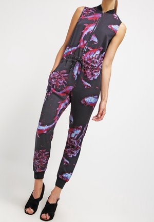 Mouwloze jumpsuit met een zwarte basis, voorzien van levendige paarse en rode bloemenpatronen. Ritssluiting en elastische boorden bij de enkels.