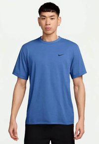 Blå idretts T-skjorte med korte ermer, rund hals, og en liten svart Nike-logo på venstre bryst. Laget av lett materiale.