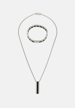 Collier chaîne en argent avec un pendentif rectangulaire noir et argent, et un bracelet assorti en argent et noir à maillons.