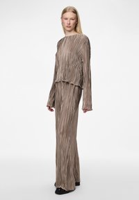 Haut taupe à manches longues plissé et jupe assortie taille haute avec un design fluide et un tissu texturé, comportant des ourlets froncés et des manches larges.