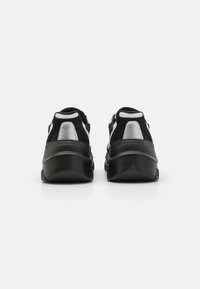 Chaussures de sport noires et grises avec une tige en daim et en maille, bout arrondi, semelle noire texturée et accents réfléchissants au niveau du talon.