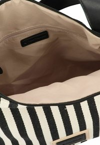 Sac rayé noir et blanc avec un extérieur en toile lisse ; fermeture éclair ; intérieur en tissu beige ; comprend une poche zippée et une étiquette de logo.