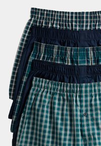 Conjunto de boxers que presenta varios patrones de cuadros en verde, azul marino y blanco, con cinturillas elásticas y un detalle de botón en un par.