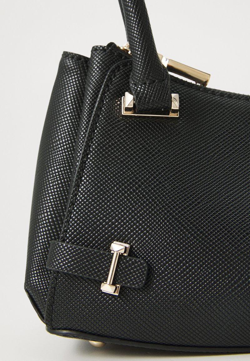 Schwarze Handtasche mit strukturierten Oberflächen, goldenen Hardware-Akzenten und einer klaren Form. Verfügt über einen auffälligen Träger und ein dekoratives Schnallendetail.