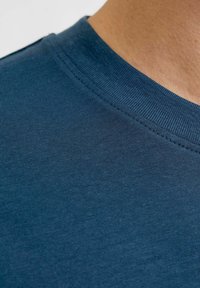 Ciemnoniebieska koszulka z okrągłym dekoltem, wykonana z gładkiej mieszanki bawełny, z prążkowanym kołnierzykiem i minimalnymi szwami dla uzyskania czystego wykończenia.