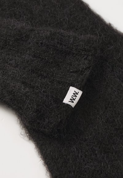 Tessuto di lana nera con una texture pelosa, caratterizzato da un'etichetta di stoffa bianca con la scritta 'W.W.' sul bordo.