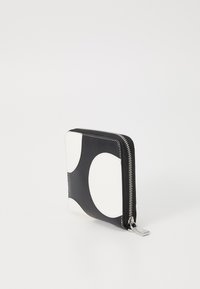 Svart og hvit glidelås lommebok med glatt lærutside, geometrisk sirkulært mønster, og detaljer i sølvhardware.
