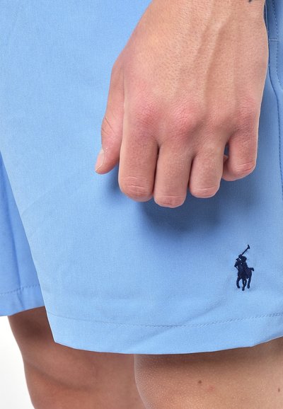 Shorts azzurri chiari realizzati in tessuto liscio, con una vestibilità classica e orlo cucito. Logo del giocatore di polo ricamato di colore blu scuro in basso a sinistra.