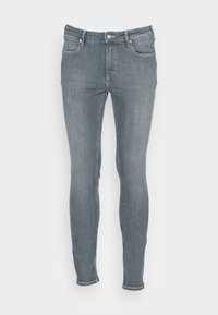 Jeans ajustados en denim azul medio con una textura desgastada. Presenta cinco bolsillos, una cremallera y detalles de costura a lo largo de las costuras.