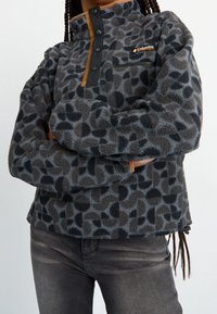 Gray fleece pullover with a leopard print, zippered chest pocket, and snap button placket. Features black accents and a high collar.