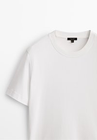 White cotton t-shirt with a round neck, short sleeves, and a smooth texture. Features a small black label on the neckline.