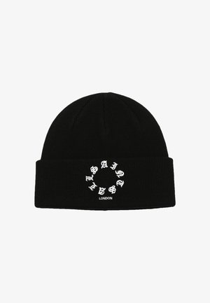 Svart stickad mössa med ribbad textur och en cirkulär grafik med "Saint" i vit skrift, placerad på framsidan.