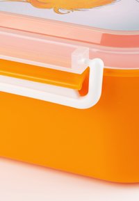 Orange plastic lunchbox with a transparent lid, featuring a white locking mechanism and a smooth texture. Accents include a colorful graphic design.