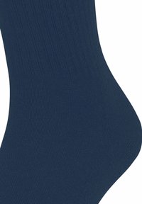 Calzino blu navy lungo fino alla caviglia con una texture a coste su sfondo bianco, che mostra un primo piano del lato del tallone.