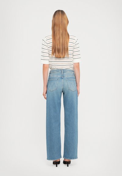 Lichtblauwe wijde jeans met een hoge taille, versleten details en gestikte achterzakken. Gepaardt met een gestreepte top met korte mouwen.