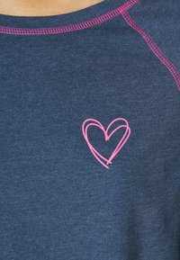 Donkerblauwe t-shirt met een ronde halslijn en roze stiksels. Bevat een geborduurd roze hartomtrek aan de linkerkant van de borst.