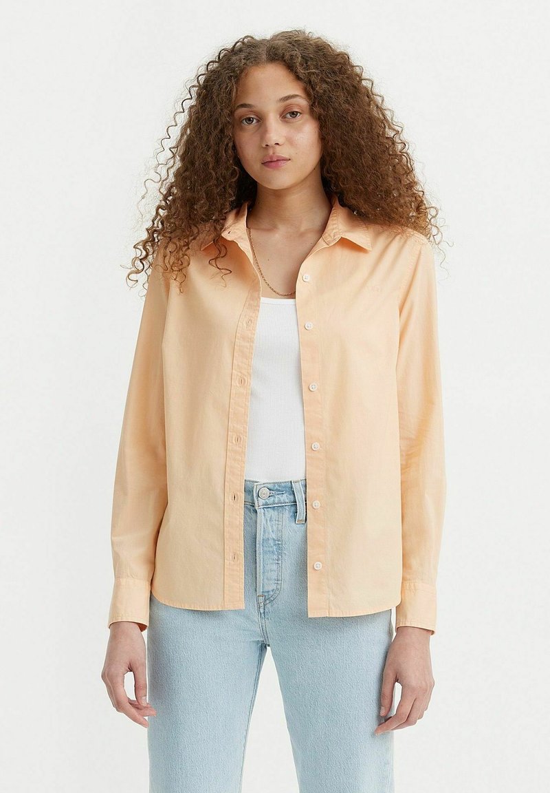 Lichtperzikkleurig button-down shirt in een katoenmix, met een kraag, lange mouwen en een relaxte pasvorm, gecombineerd met lichtblauwe spijkerbroek.