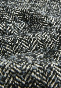 Houndstooth patterned fabric, featuring dark gray and cream colors, with a soft, textured finish and a warm, woven appearance.