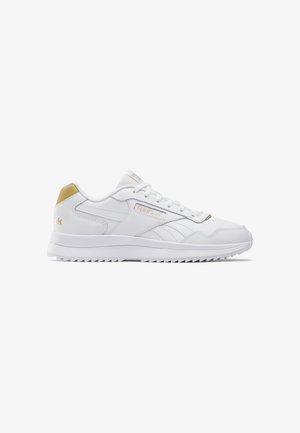Witte sportschoenen met een glad leren afwerking, voorzien van een gouden accent op de hiel en een getextureerde rubberen zool met een zigzagpatroon.