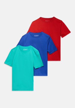 Τρία μονόχρωμα μπλουζάκια με στρογγυλή λαιμόκοψη και κοντά μανίκια στοιβαγμένα, σε τιρκουάζ, μπλε και κόκκινο, πάνω σε ανοιχτό γκρι φόντο.