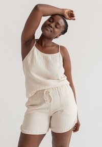 Lichtbeige, gemarmerde, geweven tanktop met verstelbare spaghetti-schouderbandjes, gecombineerd met bijpassende korte broek met een elastische tailleband en strikkoord.