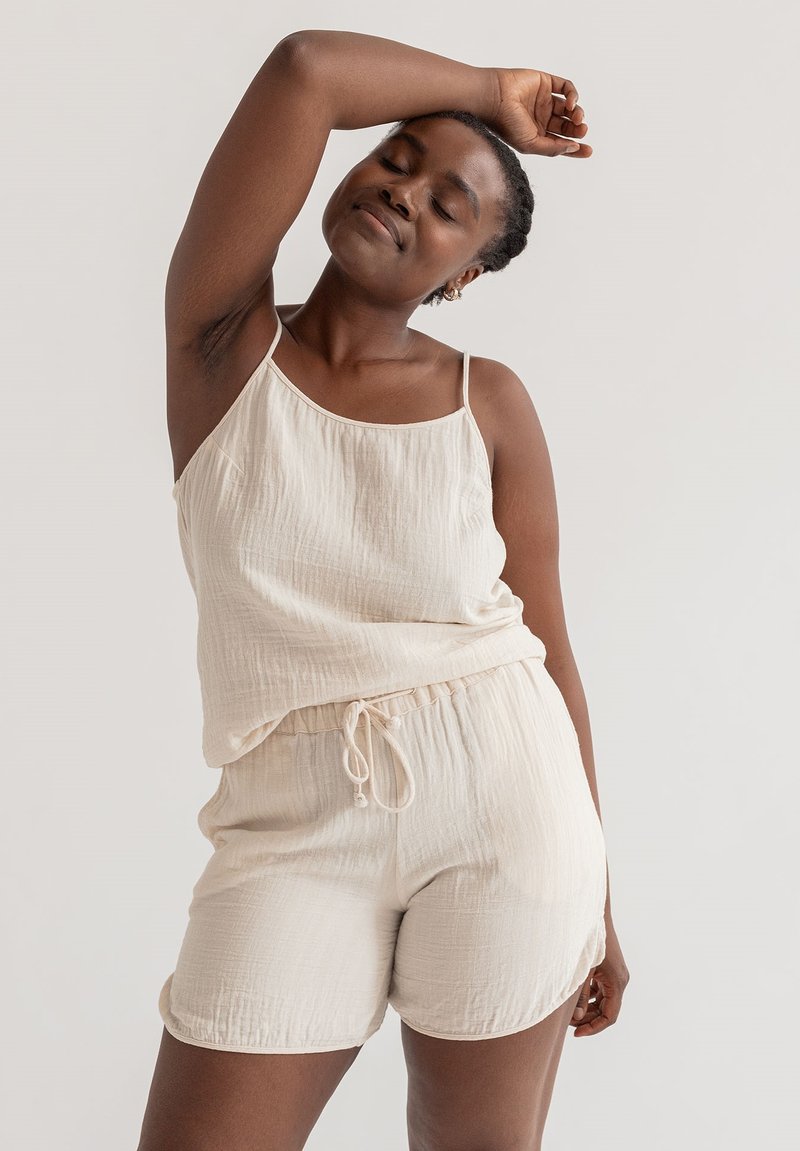 Lichtbeige, gemarmerde, geweven tanktop met verstelbare spaghetti-schouderbandjes, gecombineerd met bijpassende korte broek met een elastische tailleband en strikkoord.