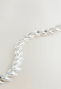 Silver chain necklace featuring interlocking links with a twisted design. Smooth, reflective surface with a metallic sheen.