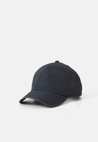 Casquette de baseball bleu marine foncé en tissu avec une visière flexible. Présente un logo noir carré avec des accents verts. Design structuré avec ventilation.