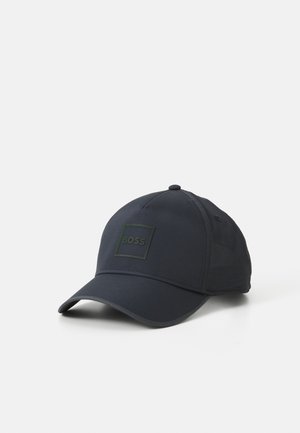 Mørkeblå baseball cap lavet af stof med en fleksibel skygge. Har et firkantet sort logo med grønne accenter. Struktureret design med ventilation.