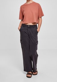 Zkrácený rustový tričko s krátkými rukávy, spárované s volnými černými cargo kalhotami s bočními kapsami a uvolněným střihem.