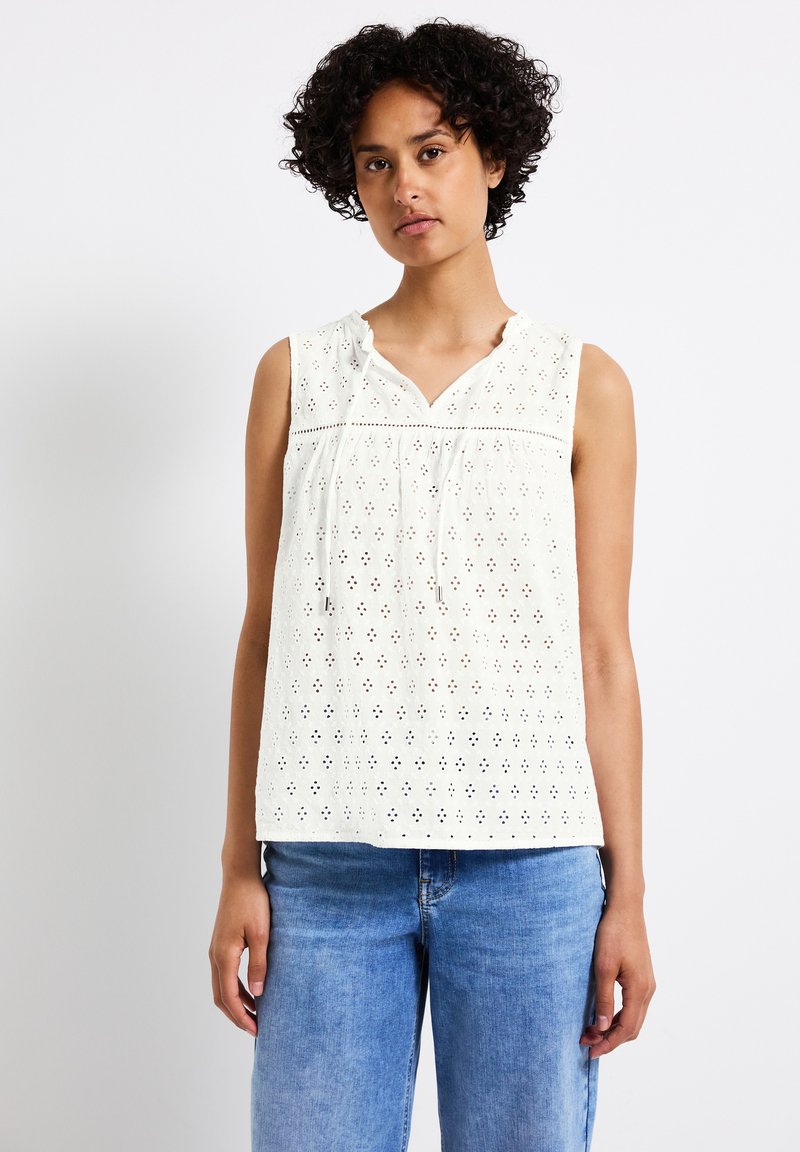 Witte, mouwloze top met een oogjesdesign en V-hals. Heeft een gatherkoord bij de hals en horizontale trimaccenten.