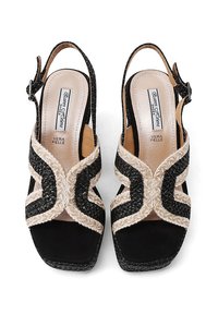 Sandali slingback neri e beige con dettagli intrecciati, punta quadrata e finitura texturizzata. Presentano una fascia con fibbia regolabile.