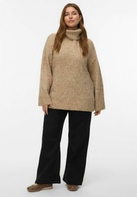Suéter de punto beige con cuello alto, puños acanalados y dobladillo. Combinado con pantalones anchos negros y zapatos marrones con cordones.