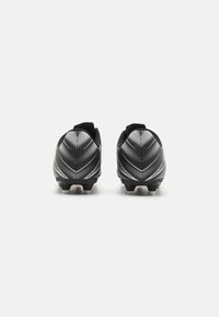 Botas de fútbol negras con un diseño texturizado que presenta patrones de puntos blancos, corte bajo y suelas con tacos para agarre.
