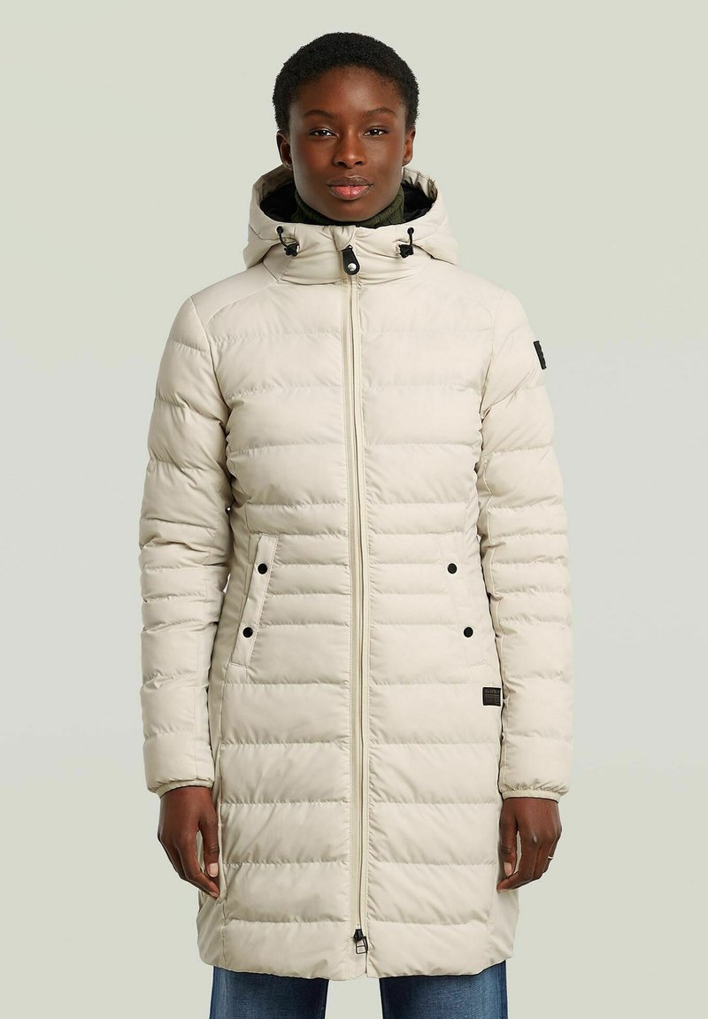 Light beige puffer coat with vertical quilted pattern, hood, and zip closure. Features black accents and side pockets. Smooth, insulated fabric.