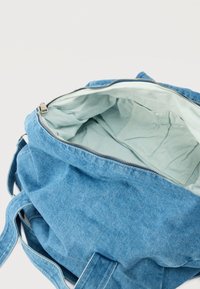 Μπλε υφασμάτινο τσάντα tote με ασημί φερμουάρ, ανοιχτή για να δείχνει το εσωτερικό από ελαφρύ μπλε ύφασμα και δύο εσωτερικές τσέπες.