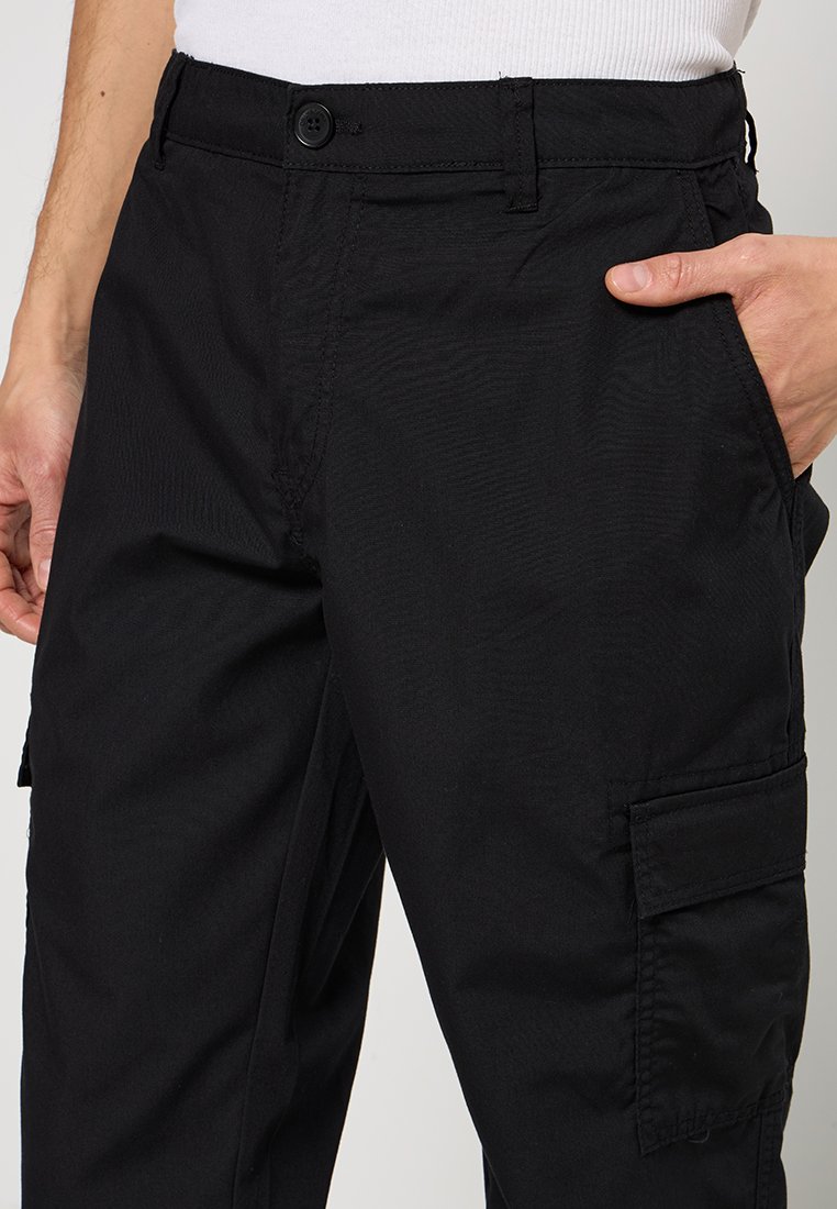 Pantalons cargo noirs en tissu durable, dotés d'une fermeture à bouton, de poches latérales et d'une finition texturée avec une coupe loose.