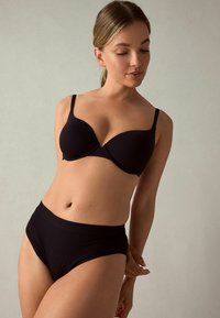 Reggiseno wireless nero con coppe sagomate e spalline regolabili, abbinato a slip neri a vita alta; tessuto liscio ed elasticizzato.