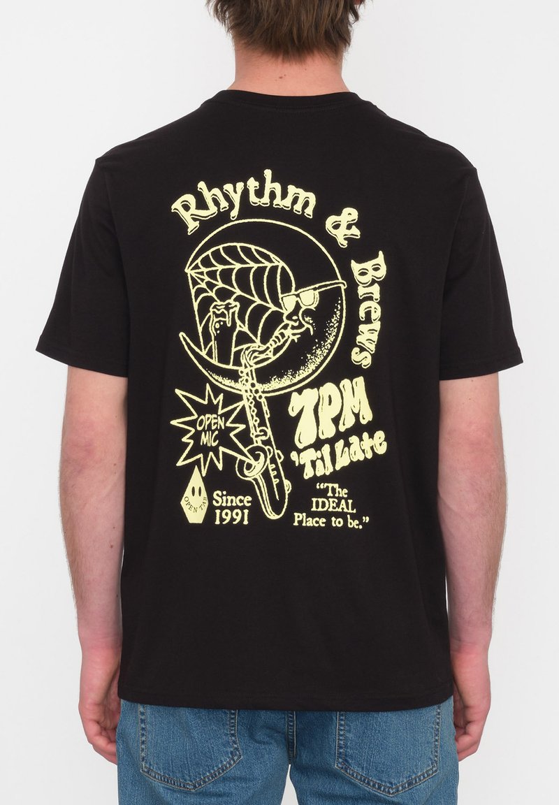 Zwarte katoenen t-shirt met een grote gele graphic op de achterkant met tekst en een ontwerp van een saxofoon, spinnenweb en muziekelementen.