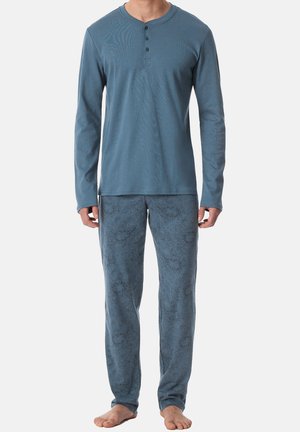 Sininen pitkähihainen henley-paita, jossa on kolme nappia, yhdistetty sinisiin kuviollisiin pyjamasiksareihin. Pehmeä kangas, rento istuvuus ja kevyt muotoilu.