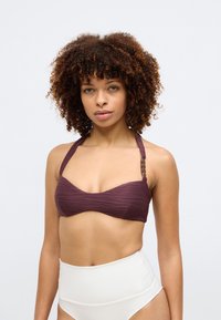 Dunkelburgunderfarbener Bikini-Oberteil mit strukturiertem, wellenförmigem Design, Halterträgern und metallischen Details, kombiniert mit weißen hochgeschnittenen Unterteilen.