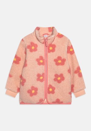 Różowa kurtka polarowa z zamkiem błyskawicznym z przodu, ozdobiona dużymi czerwonymi kwiatami z żółtymi środkami oraz jasnoróżowymi mankietami na rękawach.