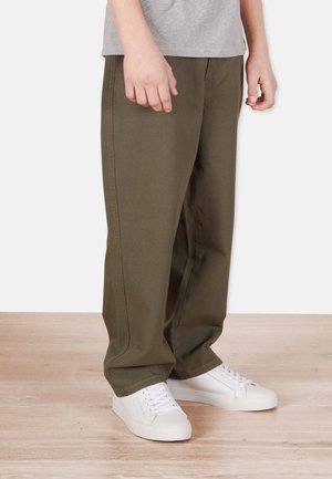 Olive green wide-leg pants in sturdy fabric with front pockets, paired with white sneakers; natural wood floor background.