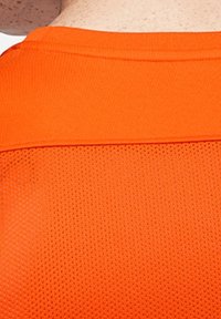 Orange atletiktrøje med et tekstureret, åndbart meshmønster. Designet har en rund halsudskæring og et kontrastfarvet stofpanel på skulderen.